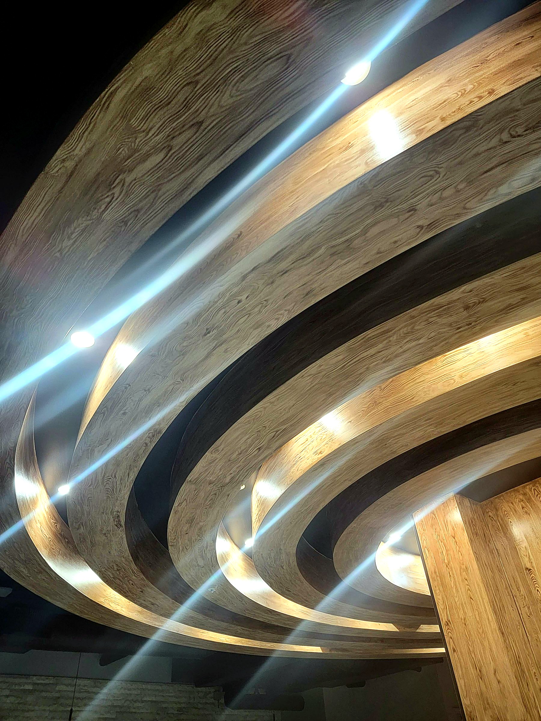 Restaurant ceiling with circular architectural forms finished in hand-painted faux wood grain
