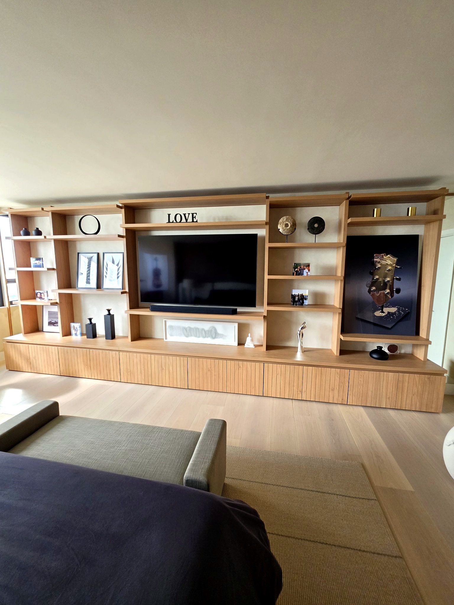 Custom oak media wall and television framed by hand-applied limewash walls in a Bal Harbour residence living room