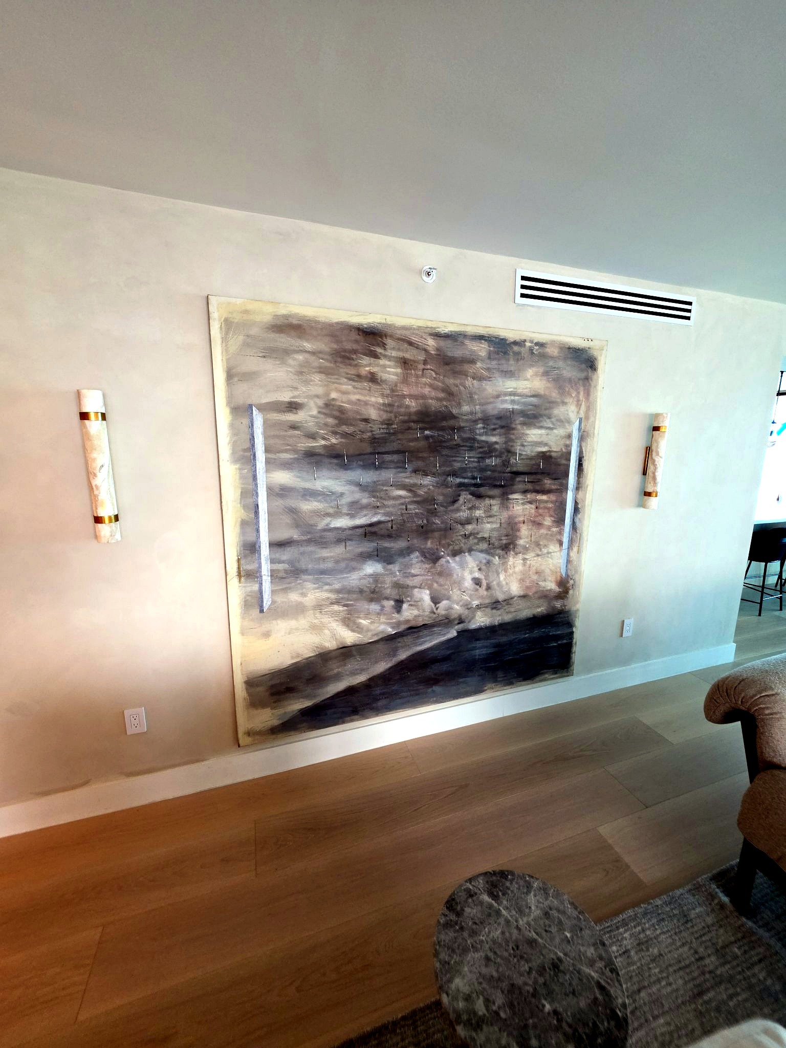 Large-scale artwork and wall sconces over a hand-applied limewash wall in a Bal Harbour residence
