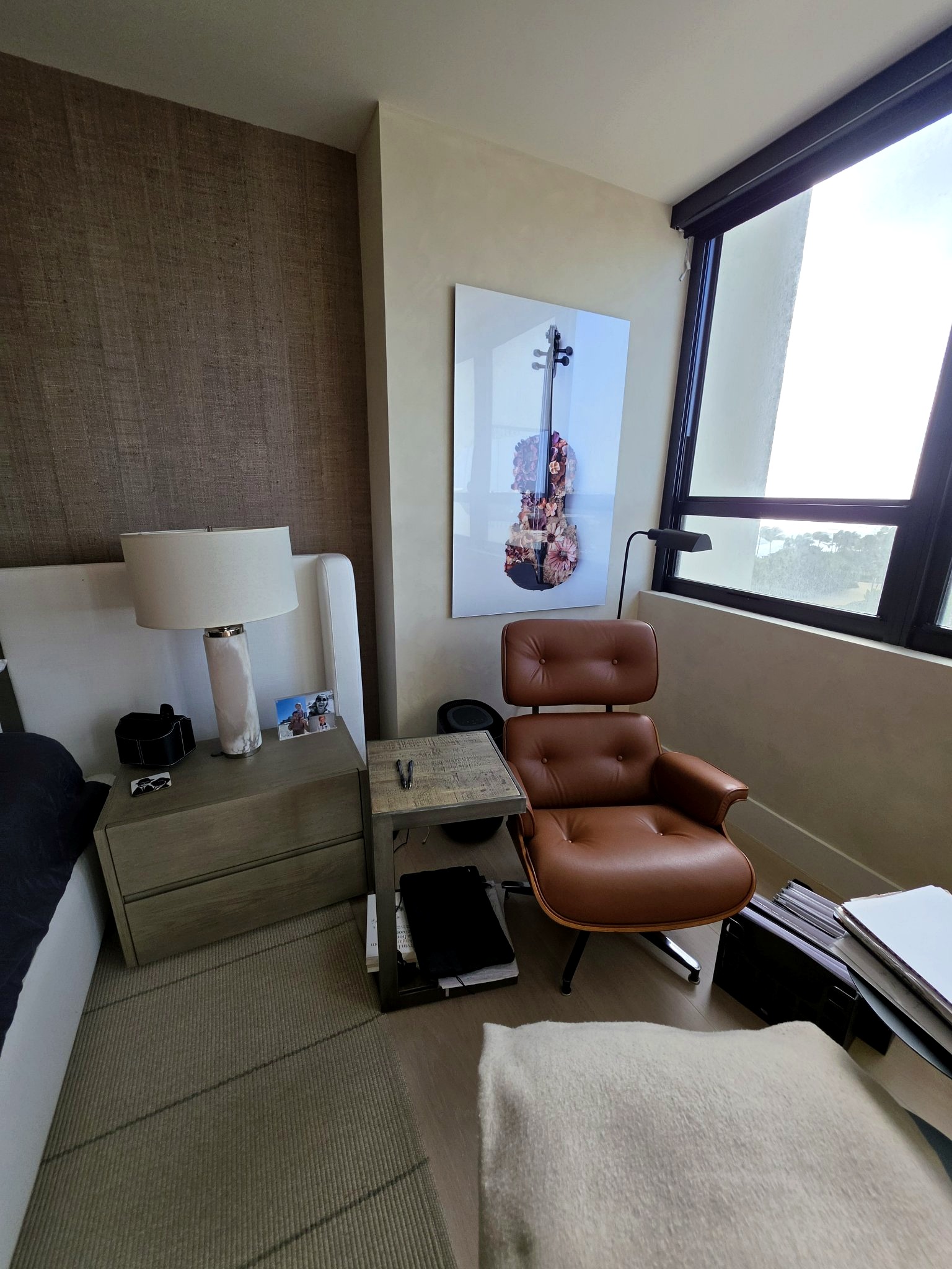 Reading corner with a leather lounge chair and violin artwork beside a hand-applied limewash wall in a Bal Harbour residence bedroom