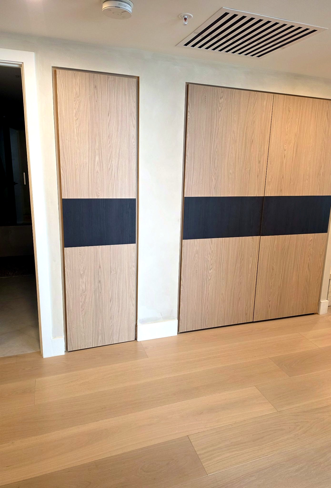 Hallway with wood wardrobe doors and softly textured hand-applied limewash walls in a Bal Harbour residence