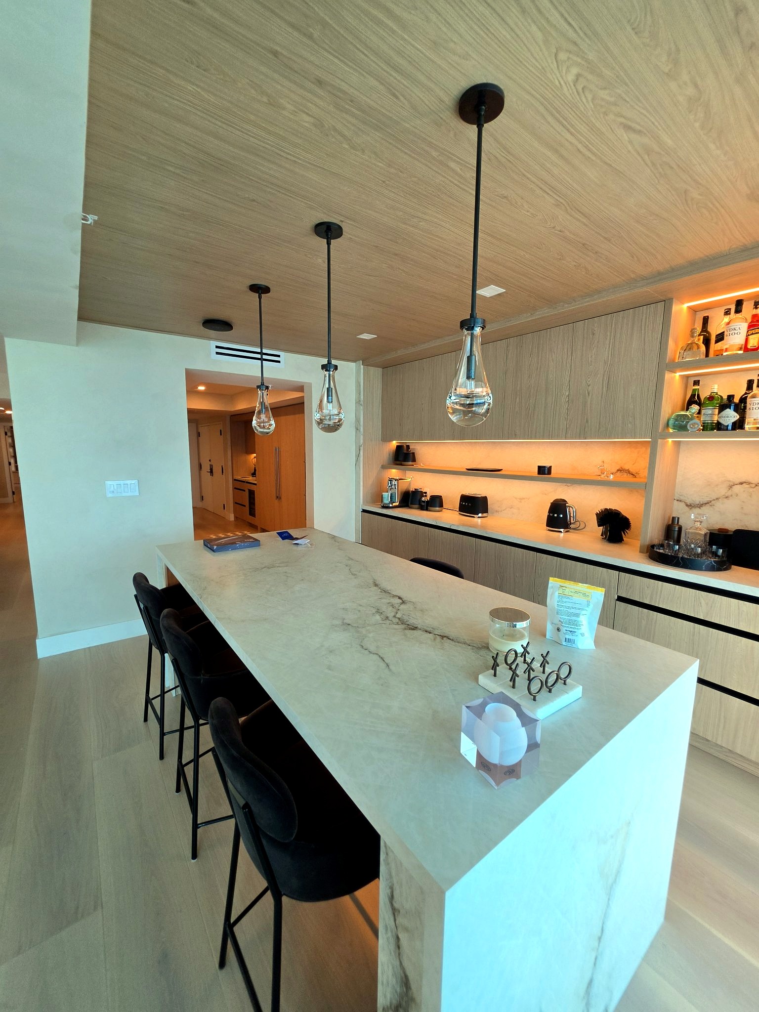 Kitchen and bar with a marble island, pendant lighting and hand-applied limewash walls in a Bal Harbour residence