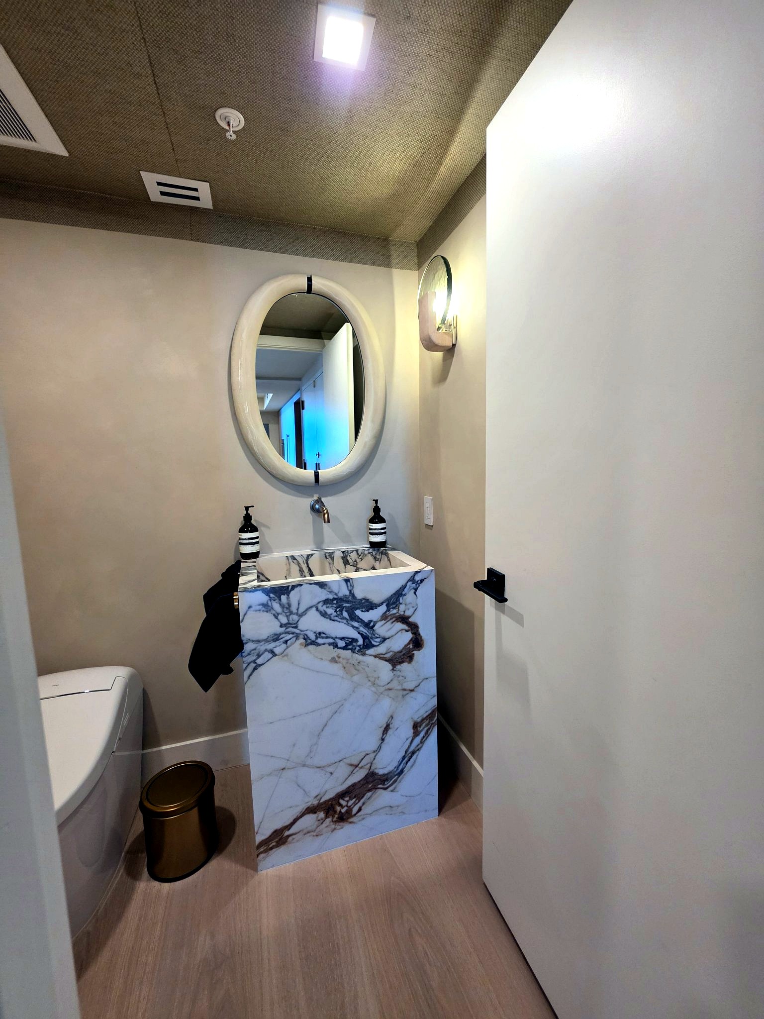 Full view of a marble powder room finished in hand-applied limewash in a Bal Harbour residence
