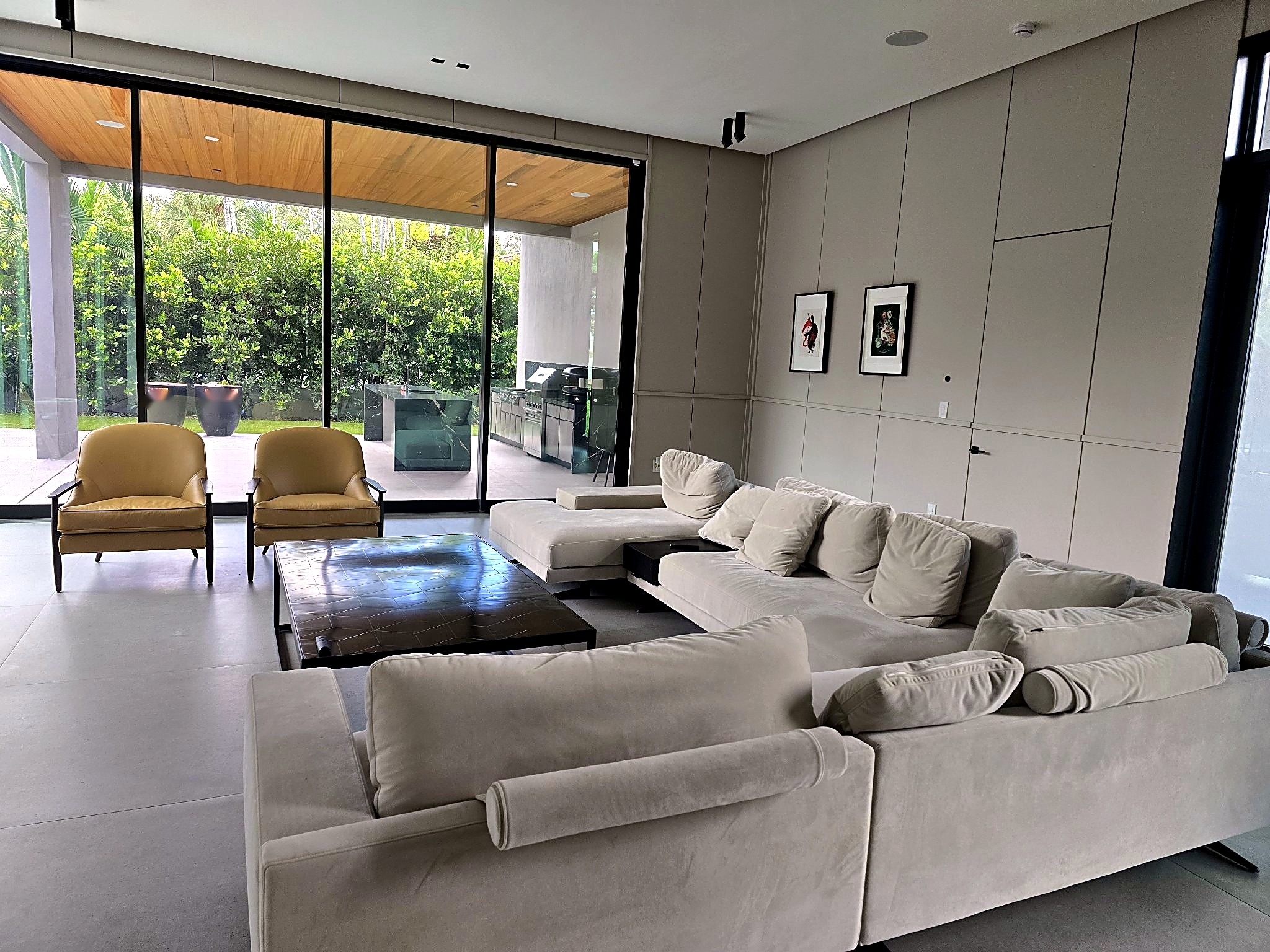 Living room with paneled walls, an L-shaped sectional and glass doors opening to the terrace