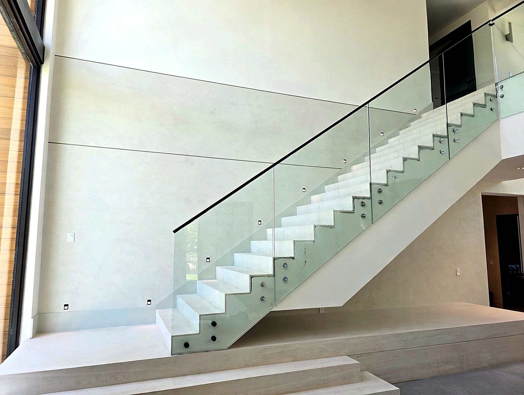 Double-height staircase wall finished in light Venetian plaster