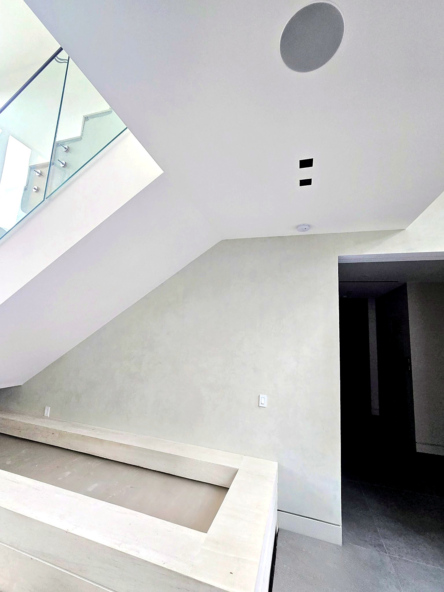 Venetian plaster wall beneath a floating glass staircase