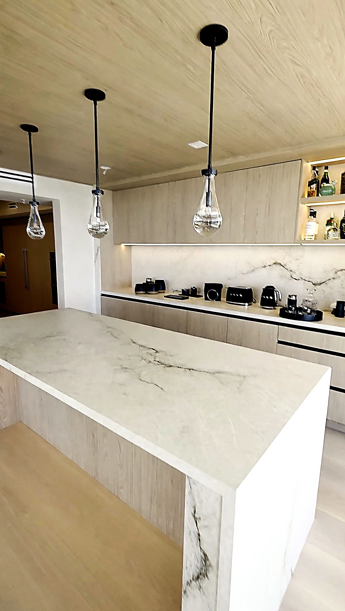 Kitchen with marble island, bar display and a glimpse of the limewash wall finish